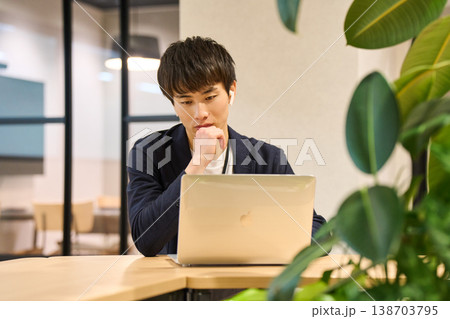 外資系IT企業のオフィスで、観葉植物の近くでノートパソコンを開き作業する若い男性 外資系IT企業のオフィスで、観葉植物の近くでノートパソコンを開き作業する若い男性 138703795