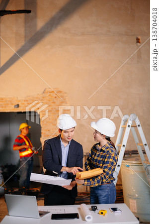 Asian construction professionals shaking hands in agreement at an indoor site. Asian construction professionals shaking hands in agreement at an indoor site. 138704018