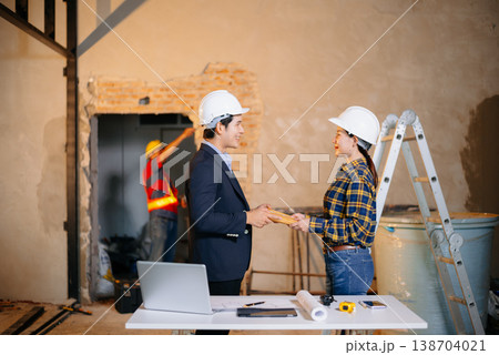 Asian construction professionals shaking hands in agreement at an indoor site. 138704021