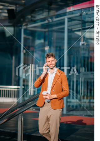 businessman works outdoors near the office holds a tablet, smiles reads good news businessman works outdoors near the office holds a tablet, smiles reads good news 138704239