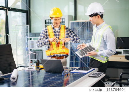 Engineers discuss solar panels and turbines in office, working on clean energy design, sustainable power Engineers discuss solar panels and turbines in office, working on clean energy design, sustainable power 138704604