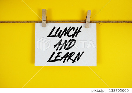 Lunch And Learn text written on paper card with rope and wooden clip hanging 138705000