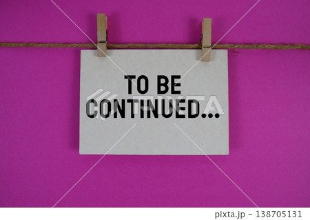 To Be Continued... text written on paper card with rope and wooden clip hanging 138705131