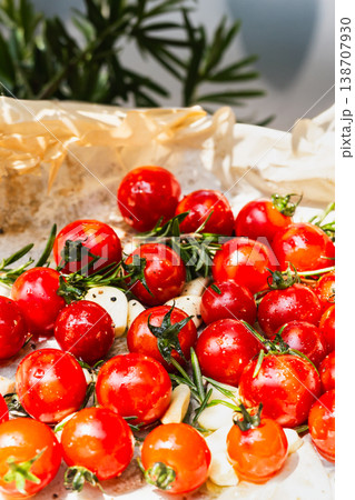 Close up vertical shot of seasoned cherry tomatoes with rosemary on baking paper. Close up vertical shot of seasoned cherry tomatoes with rosemary on baking paper. 138707930