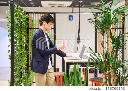 緑豊かなオフィスでスタンディングデスクを使いWeb会議をする外資系の若手男性SE 緑豊かなオフィスでスタンディングデスクを使いWeb会議をする外資系の若手男性SE 138709198