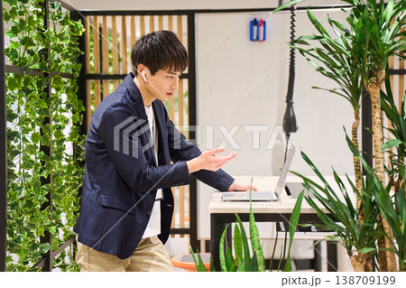 緑豊かなオフィスでスタンディングデスクを使いWeb会議をする外資系の若手男性SE 緑豊かなオフィスでスタンディングデスクを使いWeb会議をする外資系の若手男性SE 138709199