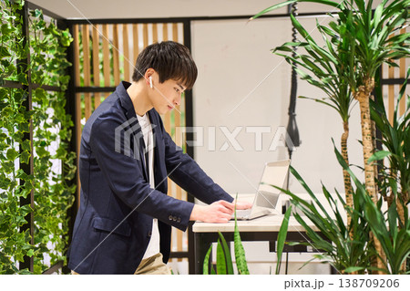 緑豊かなオフィスでスタンディングデスクを使いWeb会議をする外資系の若手男性SE 緑豊かなオフィスでスタンディングデスクを使いWeb会議をする外資系の若手男性SE 138709206