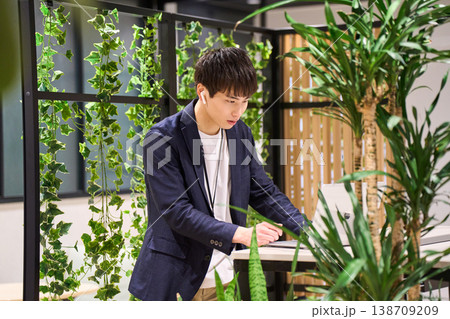 緑豊かなオフィスでスタンディングデスクを使いWeb会議をする外資系の若手男性SE 緑豊かなオフィスでスタンディングデスクを使いWeb会議をする外資系の若手男性SE 138709209