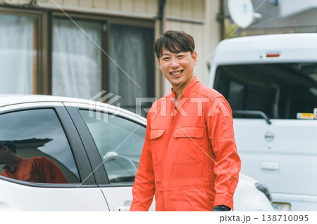乗用車とツナギ姿の男性 138710095