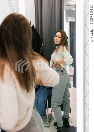 Trying on gray jeans in fitting room Trying on gray jeans in fitting room 138710410