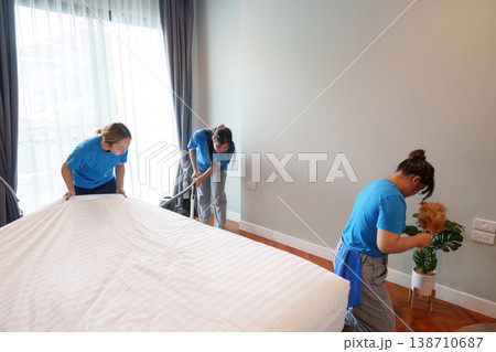 Team of cleaners tidying up a bedroom 138710687