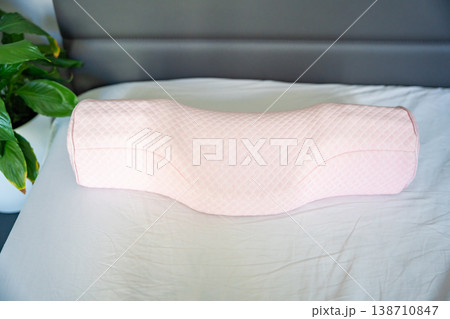 Ergonomic orthopedic pillow on bed in modern bedroom interior. Cervical support pillow for proper neck alignment, posture correction and comfortable healthy sleep at home Ergonomic orthopedic pillow on bed in modern bedroom interior. Cervical support pillow for proper neck alignment, posture correction and comfortable healthy sleep at home 138710847