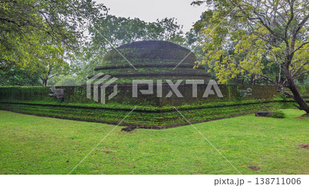 Ancient Royal Palace Ruins in Polonnaruwa, Sri Lanka. Ancient brick structure with moss-covered walls nestled in a lush green landscape under a cloudy sky Ancient Royal Palace Ruins in Polonnaruwa, Sri Lanka. Ancient brick structure with moss-covered walls nestled in a lush green landscape under a cloudy sky 138711006