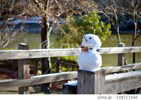 冬の公園の木製フェンスに置かれた可愛らしい手作りの雪だるま 138711594