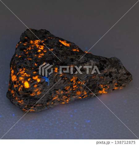Sodalite Syenite Rock with Glowing Orange and Blue Fluorescent Mineral Veins on Dark Background Sodalite Syenite Rock with Glowing Orange and Blue Fluorescent Mineral Veins on Dark Background 138712875