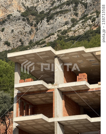 Abandoned building under construction with exposed brickwork against rocky landscape 138713588