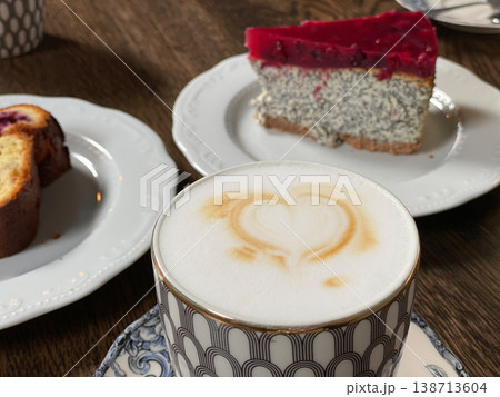 Cappuccino with heart-shaped foam art and poppy seed cake on decorative plates in a cozy setting 138713604