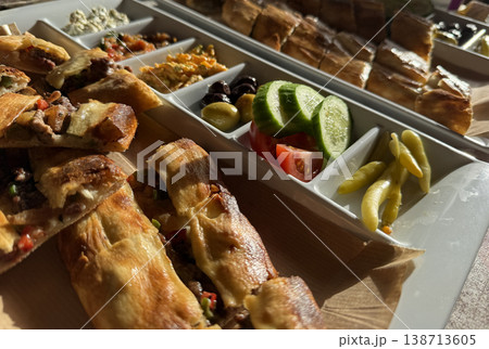 Turkish pide and assorted appetizers served on a platter under warm sunlight. 138713605