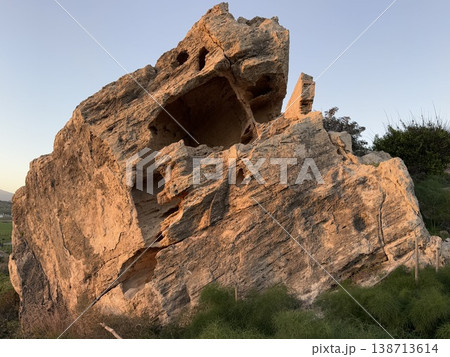 Large rock formation in natural landscape with sunlight illuminating surface texture 138713614