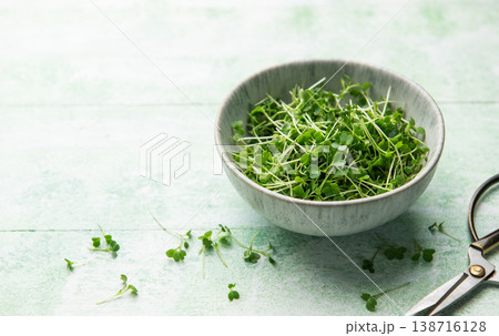 Fresh microgreens in bowl with scissors on green table Fresh microgreens in bowl with scissors on green table 138716128