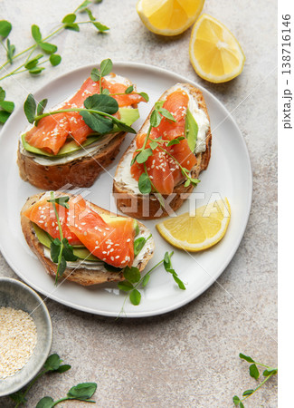 Salmon avocado toasts with cream cheese and lemon on plate Salmon avocado toasts with cream cheese and lemon on plate 138716146