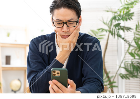 スマホを見て悩む男性 138718699