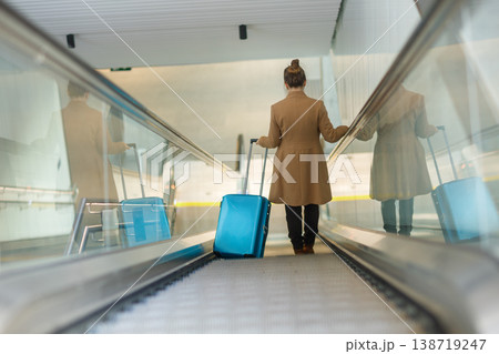Traveler with Blue Suitcase on Moving Walkway Traveler with Blue Suitcase on Moving Walkway 138719247