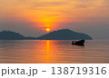 Serene sunrise in Phuket over calm sea with silhouette of boat and distant islands, creating tranquil atmosphere 138719316