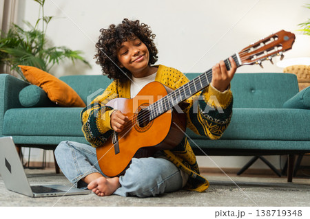 Blogger guitarist. Happy African American girl blogger playing guitar singing song recording vlog. Social media influencer woman streaming recording at home studio. Music content creator broadcast Blogger guitarist. Happy African American girl blogger playing guitar singing song recording vlog. Social media influencer woman streaming recording at home studio. Music content creator broadcast 138719348