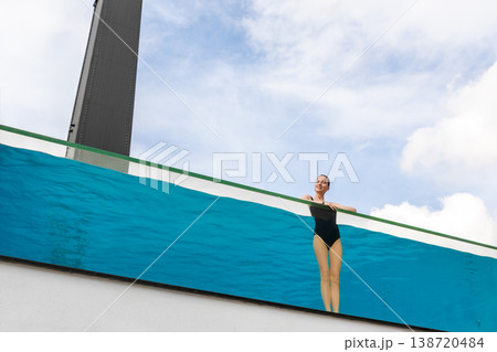 Young adult caucasian sporty slim smiling relaxing woman enjoy stand in pool with clear blue water and trasparent wall edge against sky at luxury spa resort. Healthy lifestyle and wellness concept Young adult caucasian sporty slim smiling relaxing woman enjoy stand in pool with clear blue water and trasparent wall edge against sky at luxury spa resort. Healthy lifestyle and wellness concept 138720484