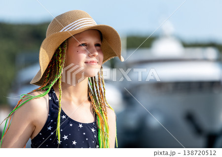 Girl wearing straw hat swimsuit stand sea luxury yachts marina during sunny summer vacation. Travel lifestyle, childhood freedom and seaside tourism atmosphere with blue water and resort background 138720512