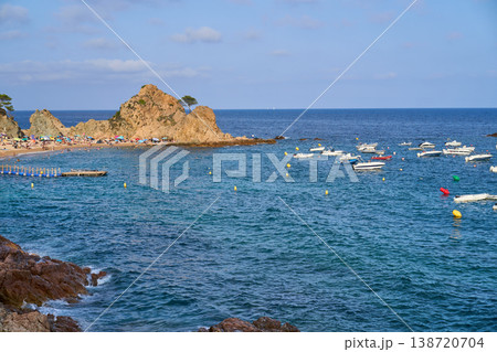 A scenic view of the coast of Tossa de Mar with boats, beachgoers, and the stunning Mediterranean sea. 138720704