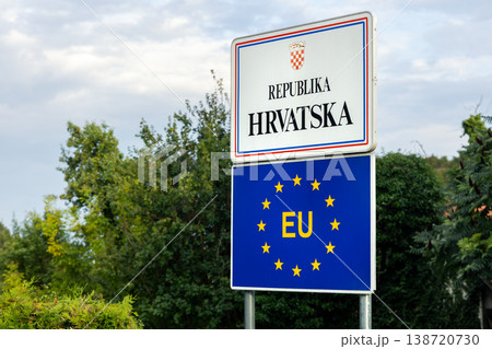 Border sign showing Republika Hrvatska EU emblem beside rural greenery cloudy sky. Croatia entrance marker European Union membership crossborder travel, sovereignty, tourism routes and Balkan gateway Border sign showing Republika Hrvatska EU emblem beside rural greenery cloudy sky. Croatia entrance marker European Union membership crossborder travel, sovereignty, tourism routes and Balkan gateway 138720730