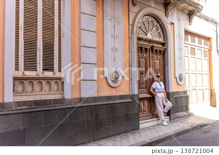 Confident Woman Leaning On Ornate Historic Facade With Vintage Door In European City 138721004
