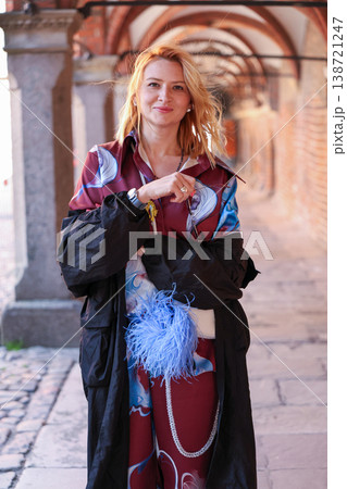 Elegant adult woman walking through a historic brick archway in a European style city. Elegant adult woman walking through a historic brick archway in a European style city. 138721247