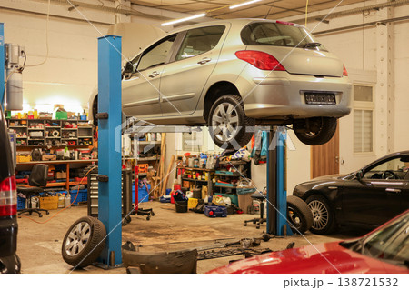 Passenger car elevated on hydraulic lift inside a professional auto workshop. Passenger car elevated on hydraulic lift inside a professional auto workshop. 138721532