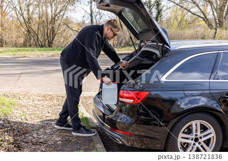 Man taking container from car trunk roadside situation fuel or emergency transport concept 138721836