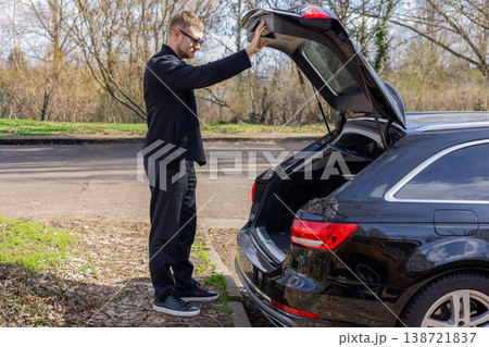 Man opening car trunk outdoors preparing for travel or storage modern vehicle lifestyle concept Man opening car trunk outdoors preparing for travel or storage modern vehicle lifestyle concept 138721837