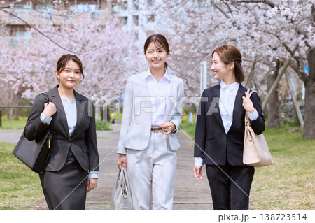 桜並木の下を歩く三人のスーツ姿の若い女性・春の就職活動・新入社員イメージ 138723514