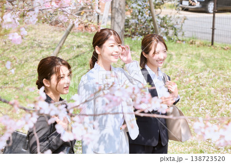 桜の下を歩く新入社員の若い女性3人・春のビジネスシーン・スーツ姿のフレッシュマン 138723520
