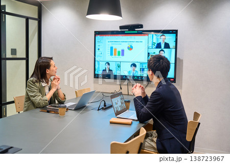 会議室の大型モニターでオンライン会議を行うIT企業の男女 138723967