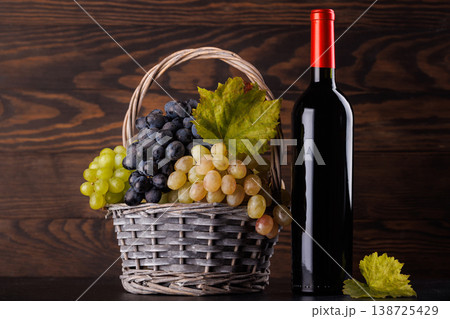 Red wine bottle with a glass and basket of fresh grapes Red wine bottle with a glass and basket of fresh grapes 138725429
