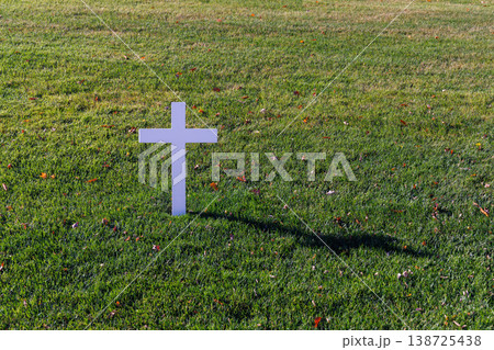 Grave cross surrounded by green lawn in a cemetery Grave cross surrounded by green lawn in a cemetery 138725438