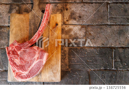 Raw tomahawk steak on cutting board Raw tomahawk steak on cutting board 138725556