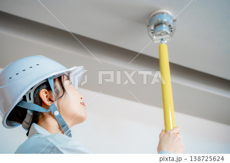 自動火災報知設備の点検をする作業着の女性 138725624