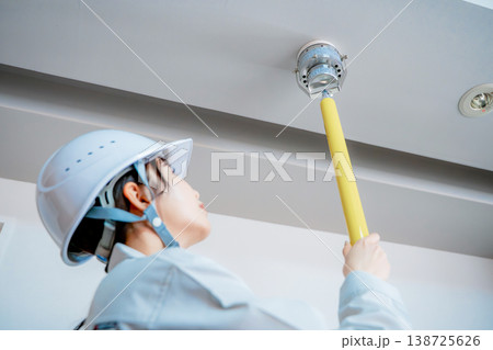 自動火災報知設備の点検をする作業着の女性 138725626