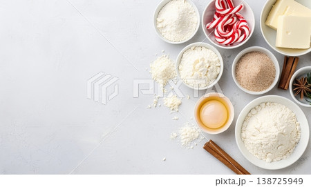 Flour, butter, candy canes, sugar, and baking items are arranged neatly on a white surface, ready for making dough. The setting shows a planned preparation space Flour, butter, candy canes, sugar, and baking items are arranged neatly on a white surface, ready for making dough. The setting shows a planned preparation space 138725949