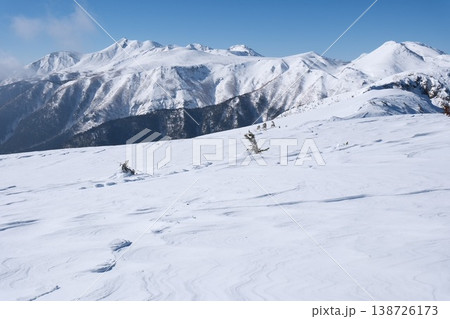 澄み渡る青空と広大な雪原に刻まれた風紋、雄大な冬の雪山連峰 澄み渡る青空と広大な雪原に刻まれた風紋、雄大な冬の雪山連峰 138726173