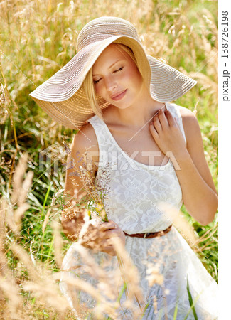 Summer, hat and smile with woman in field for travel, vacation and holiday. Relax, peace and nature with female person and grass in countryside meadow for calm environment, spring and sunshine 138726198