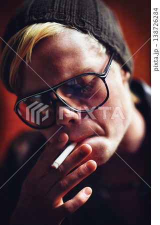 Face, addiction and a boy smoking a cigarette closeup for nicotine or tobacco dependency in sunglasses. Style, smoke and bad habit with a young person inhaling an addictive substance for cancer Face, addiction and a boy smoking a cigarette closeup for nicotine or tobacco dependency in sunglasses. Style, smoke and bad habit with a young person inhaling an addictive substance for cancer 138726284